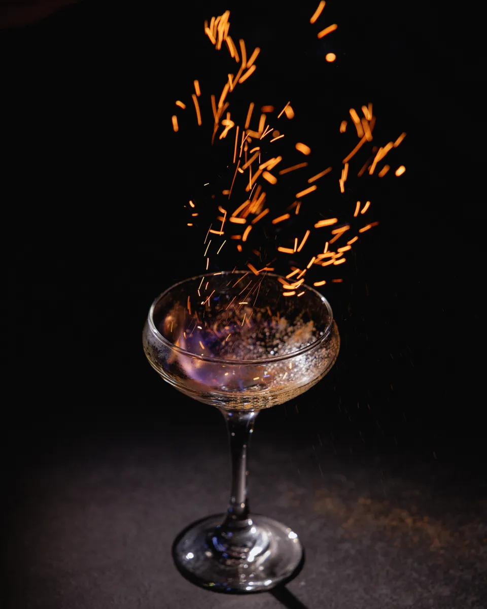 Cocktail throwing golden sparks against a black background
