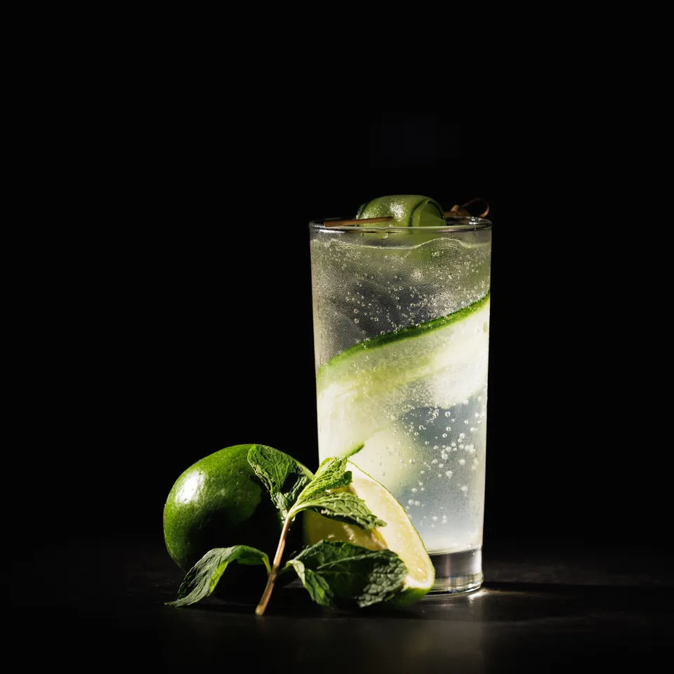 Highball cocktail with fresh lime and mint on black