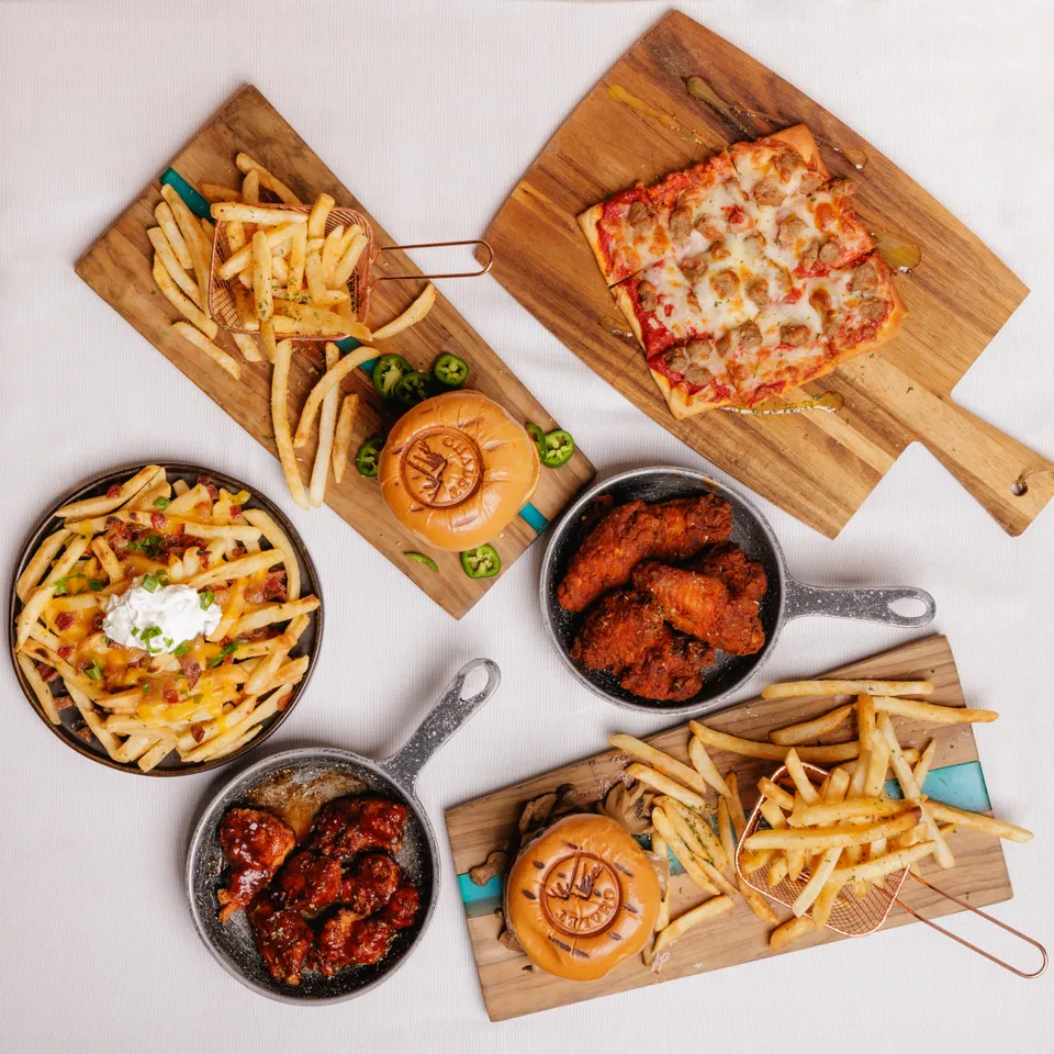 Overhead spread of pizza, wings, burgers, and loaded fries