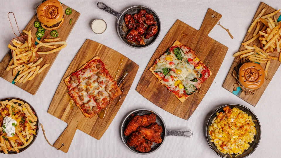 Wide overhead banner of a full pub food spread on serving boards
