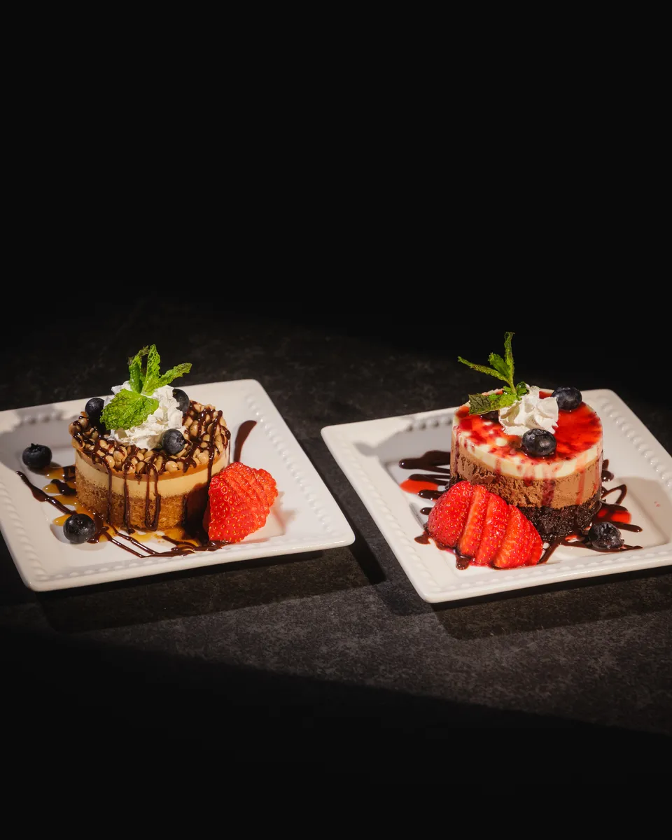 Plated strawberry cheesecake desserts with chocolate drizzle